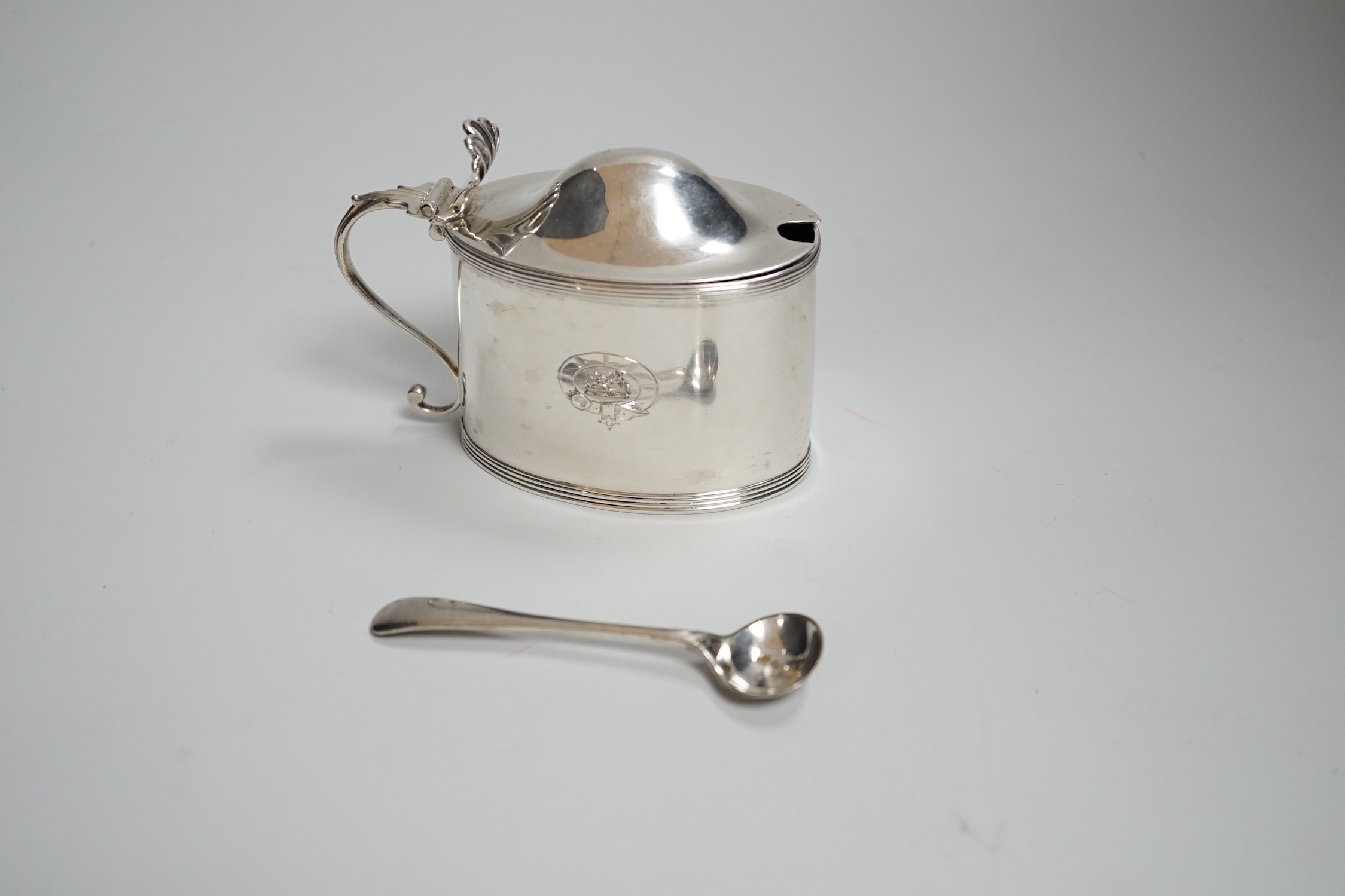 A George III oval silver drum mustard, with domed lid, blue glass liner and associated plated spoon, makers Peter, Anne and William Bateman, London 1799, 110 grams